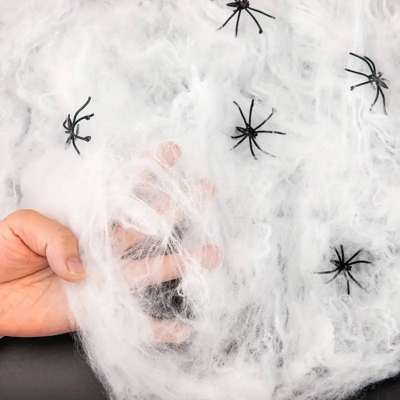 White stretchable spider web with attached black spider figures, shown being held
