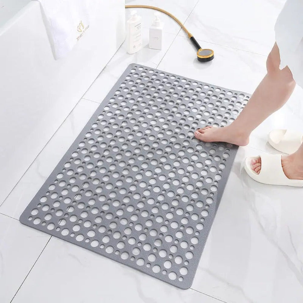 Gray non-slip shower mat with round drainage holes, placed on bathroom floor