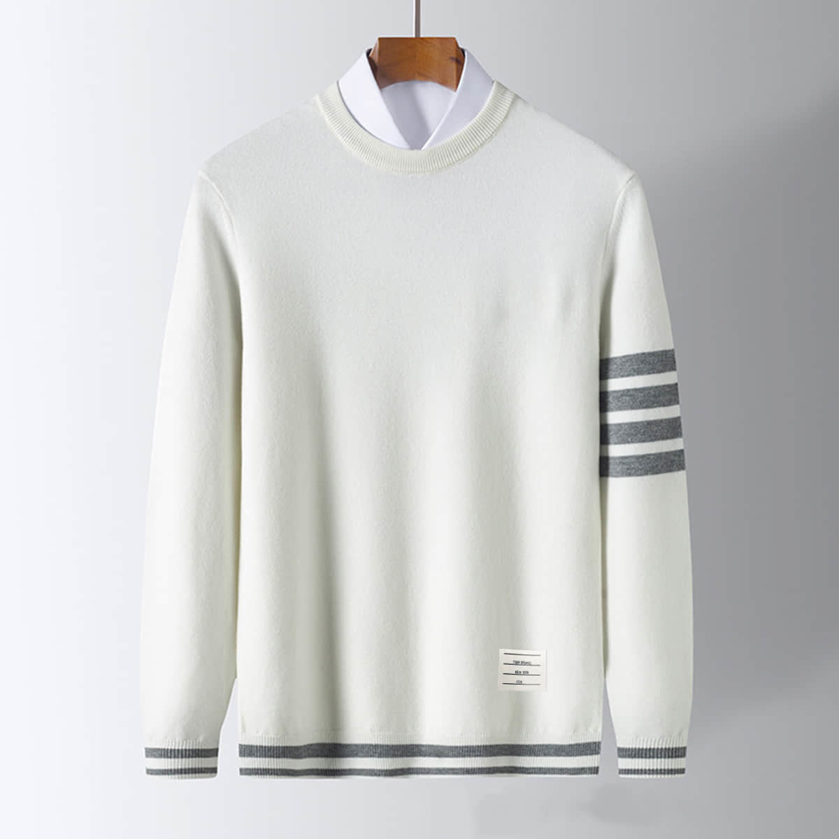 Men's pullover sweater, off-white knit with dark striped sleeve cuffs and hem band.