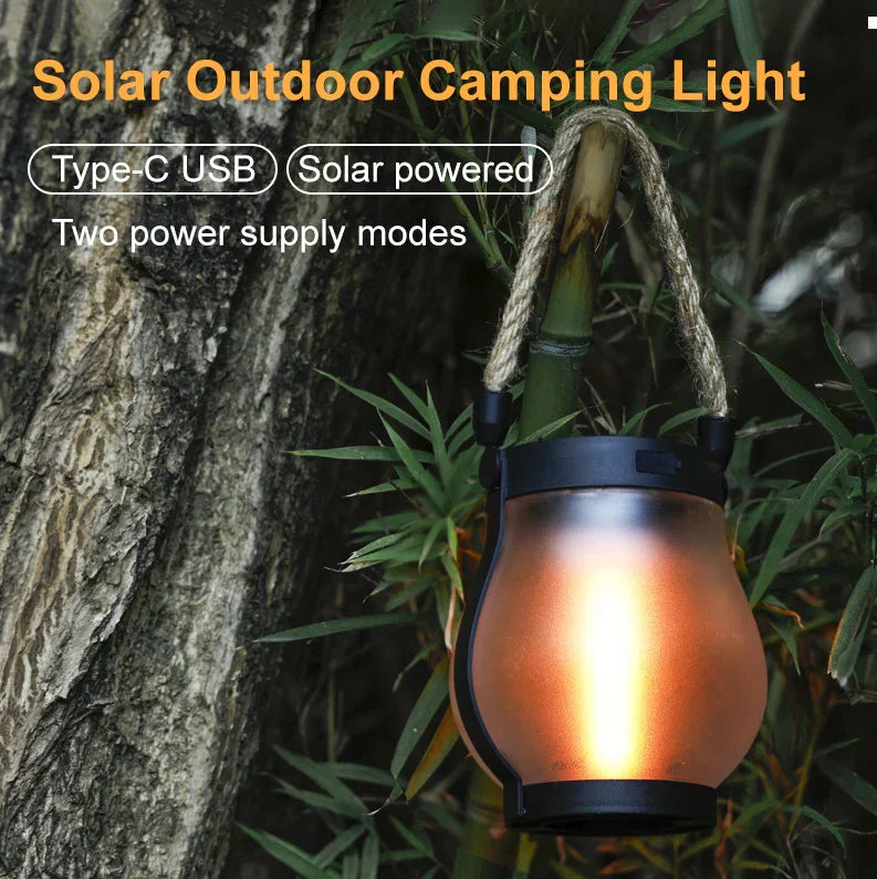 Solar powered outdoor camping lantern with rope handle and glowing flame in glass.