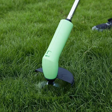 Cordless mini weed trimmer trimming lawn edge, green handle with black base guard