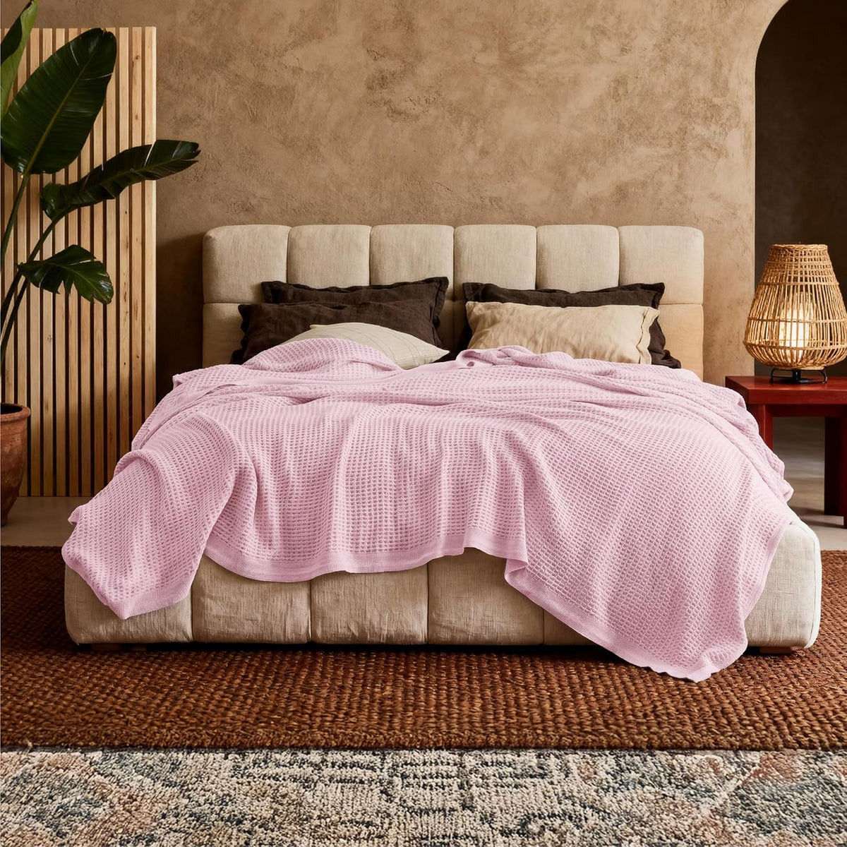 Pink cotton waffle-weave cooling blanket, draped over a bed with folded edges.