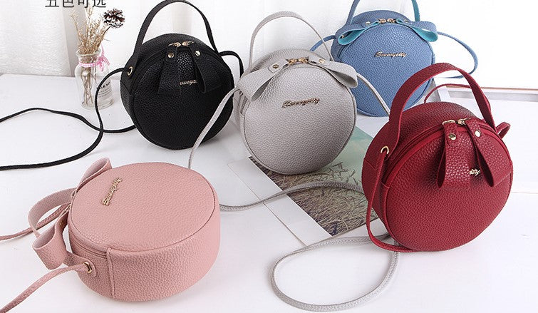 Assorted round mini crossbody bags in black, blue, grey, red, and pink with straps
