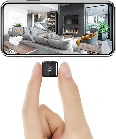 Mini wireless security camera with front lens, small black cube held in fingers