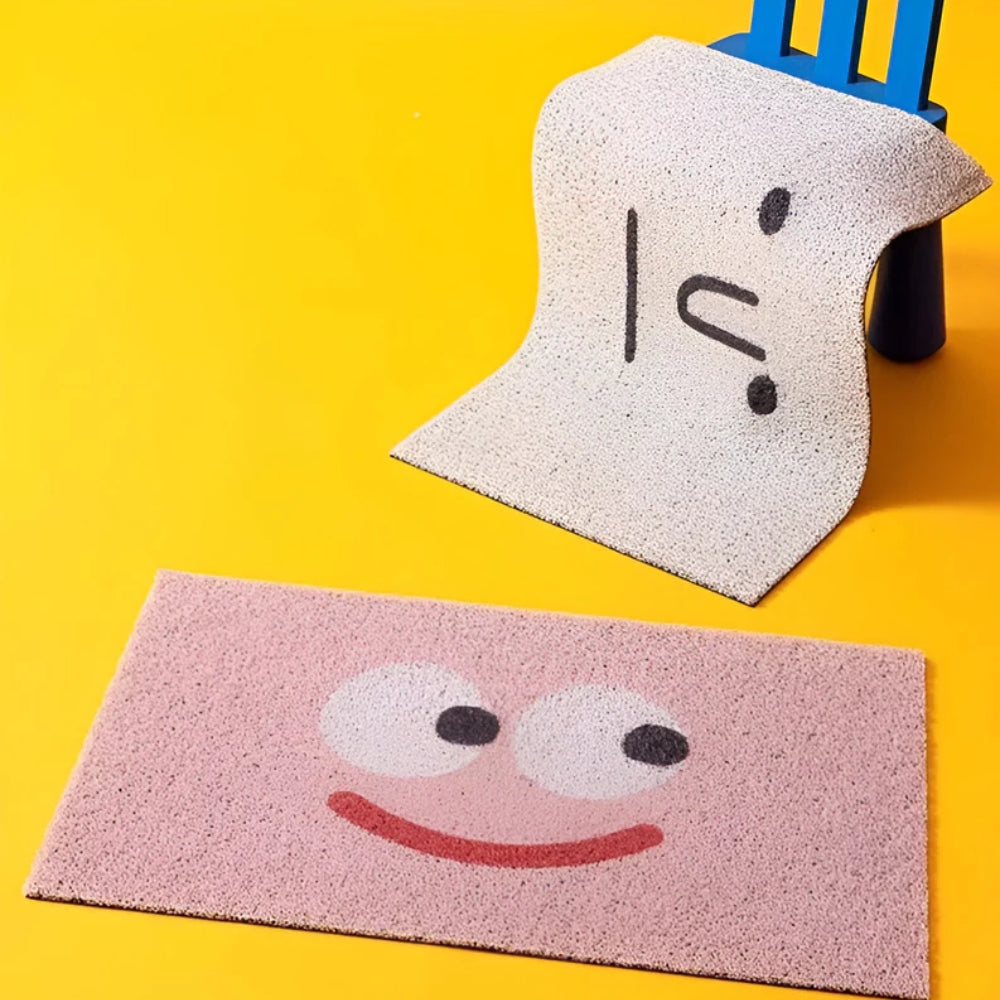 Two doormats with cartoon face designs on a yellow background