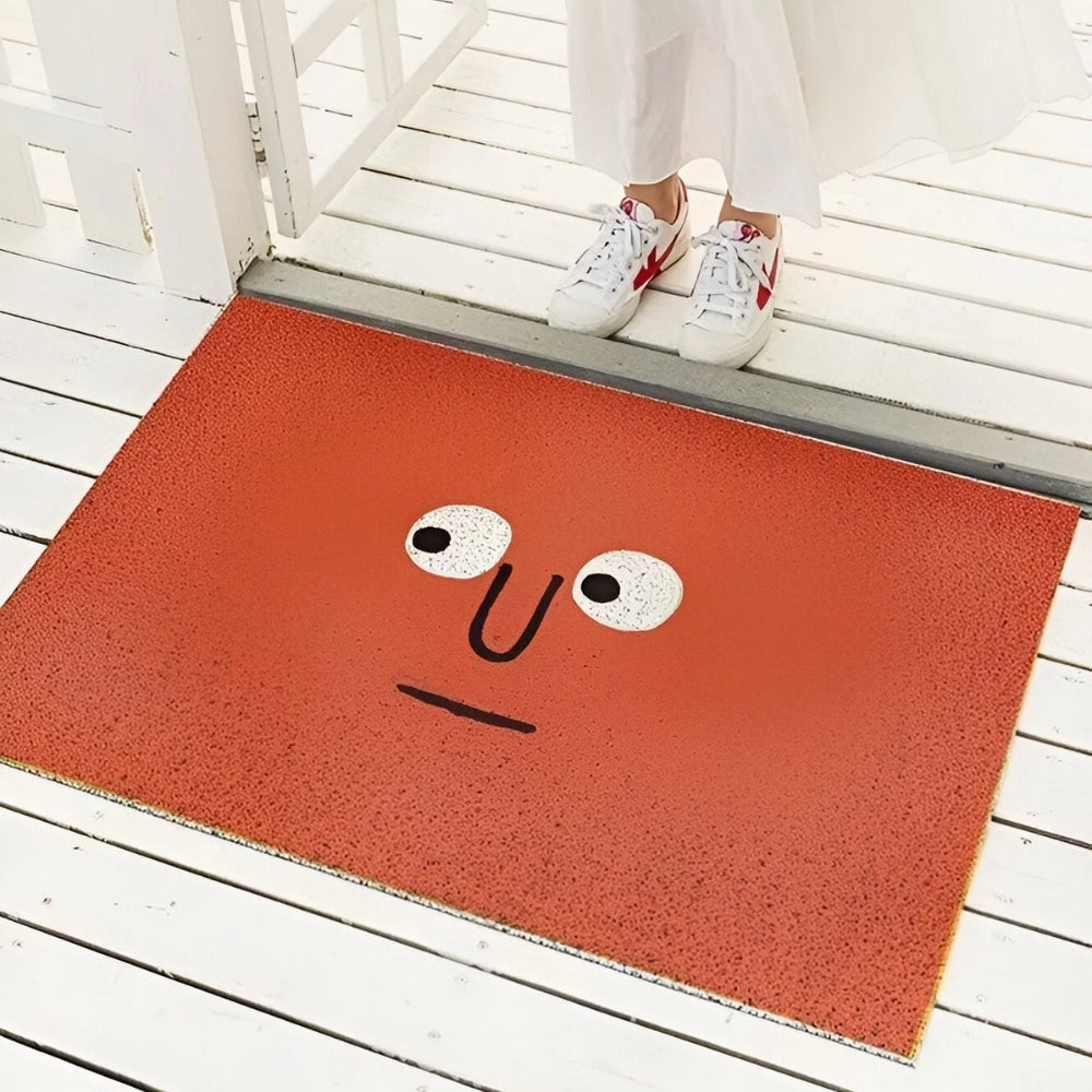 Red entrance doormat with black-and-white smiling face graphic