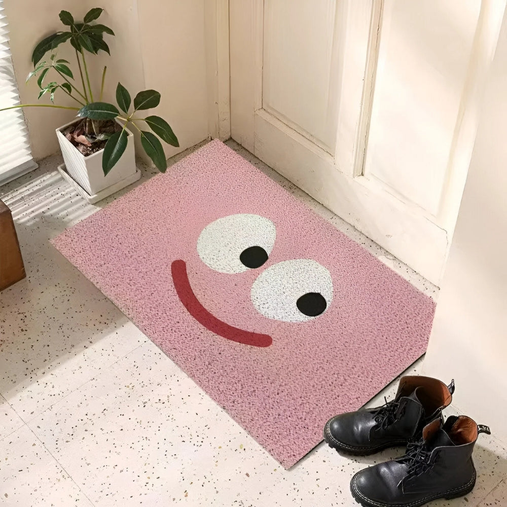 Pink entrance doormat with smiling face graphic and black-dot eyes