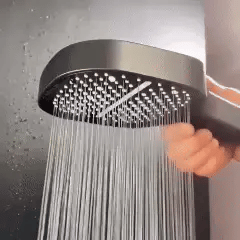 Round shower head spraying a dense sheet of water from a full nozzle array
