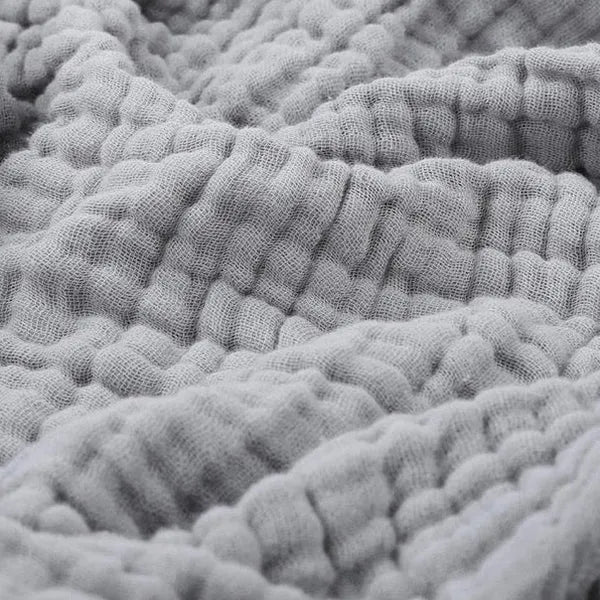 Cotton muslin throw blanket in gray with textured crinkle weave and wavy folds