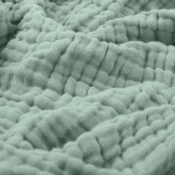 Cotton muslin throw blanket in green with soft crinkle texture and raised folds