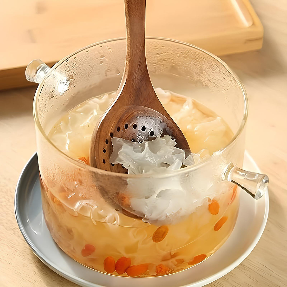 Teak wooden utensil soaking in a bowl with ice and floating flower petals