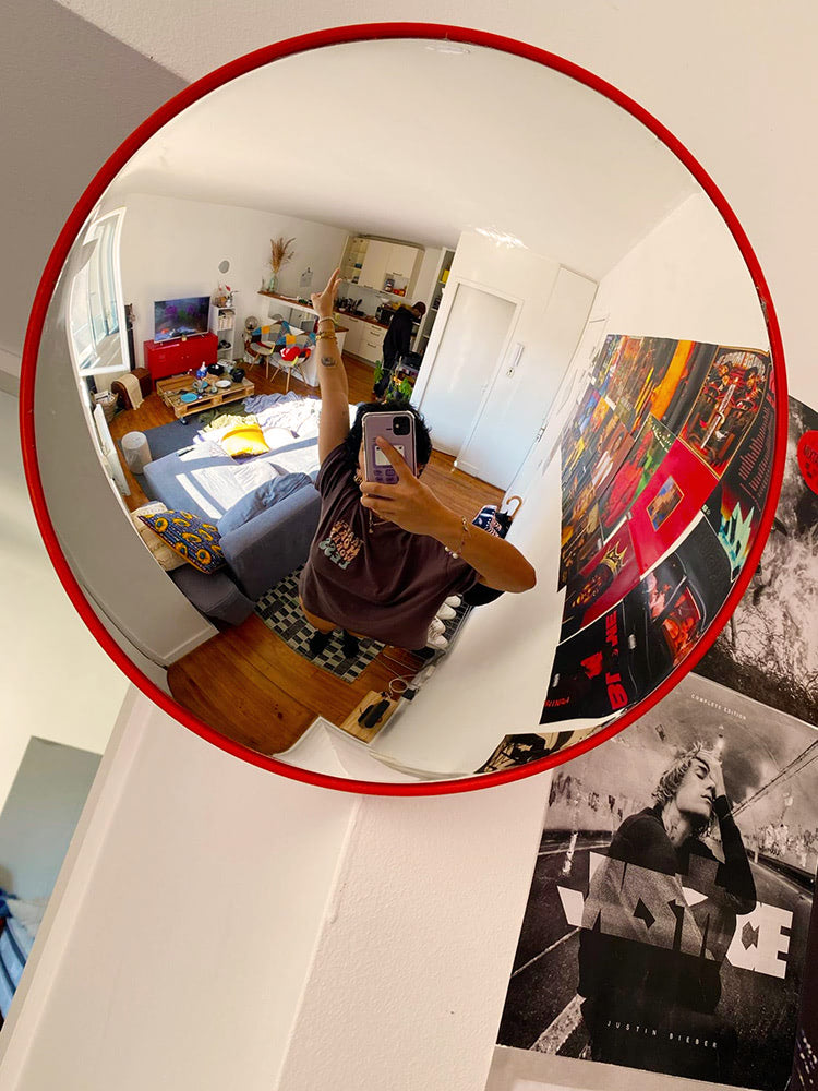 Round wall mirror with orange rim showing a room interior reflection