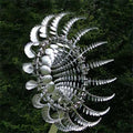 Metal garden wind spinner with swirling silver disc blades on a central pole.