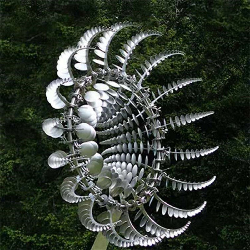 Metal garden wind spinner with swirling silver disc blades on a central pole.