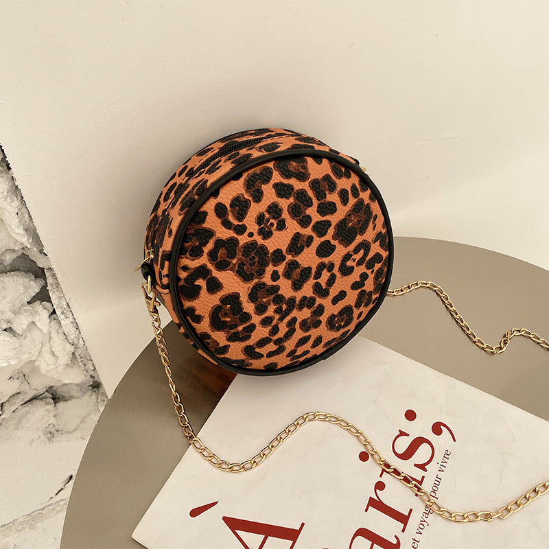 Leopard print round mini crossbody bag with gold-tone chain strap and zipper top