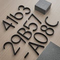 Black floating metal house numbers, assorted digits laid on wood