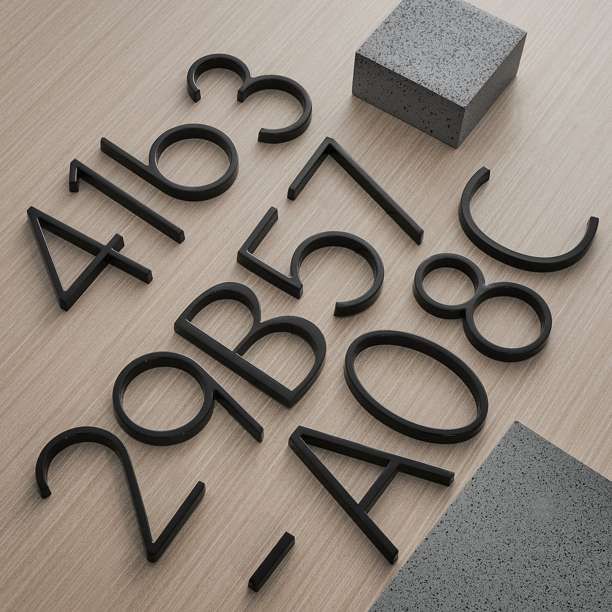 Black floating metal house numbers, assorted digits laid on wood
